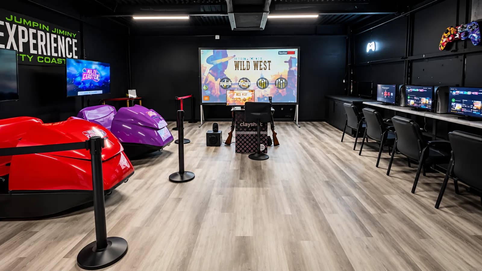 The Gaming Zone: roller coaster simulator seats, a row of gaming stations, and the large interactive screen