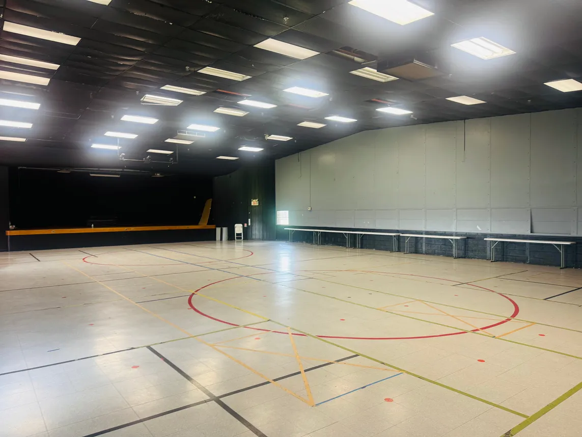 Open gym floor with court markings and a stage in the Gym/Multipurpose Room